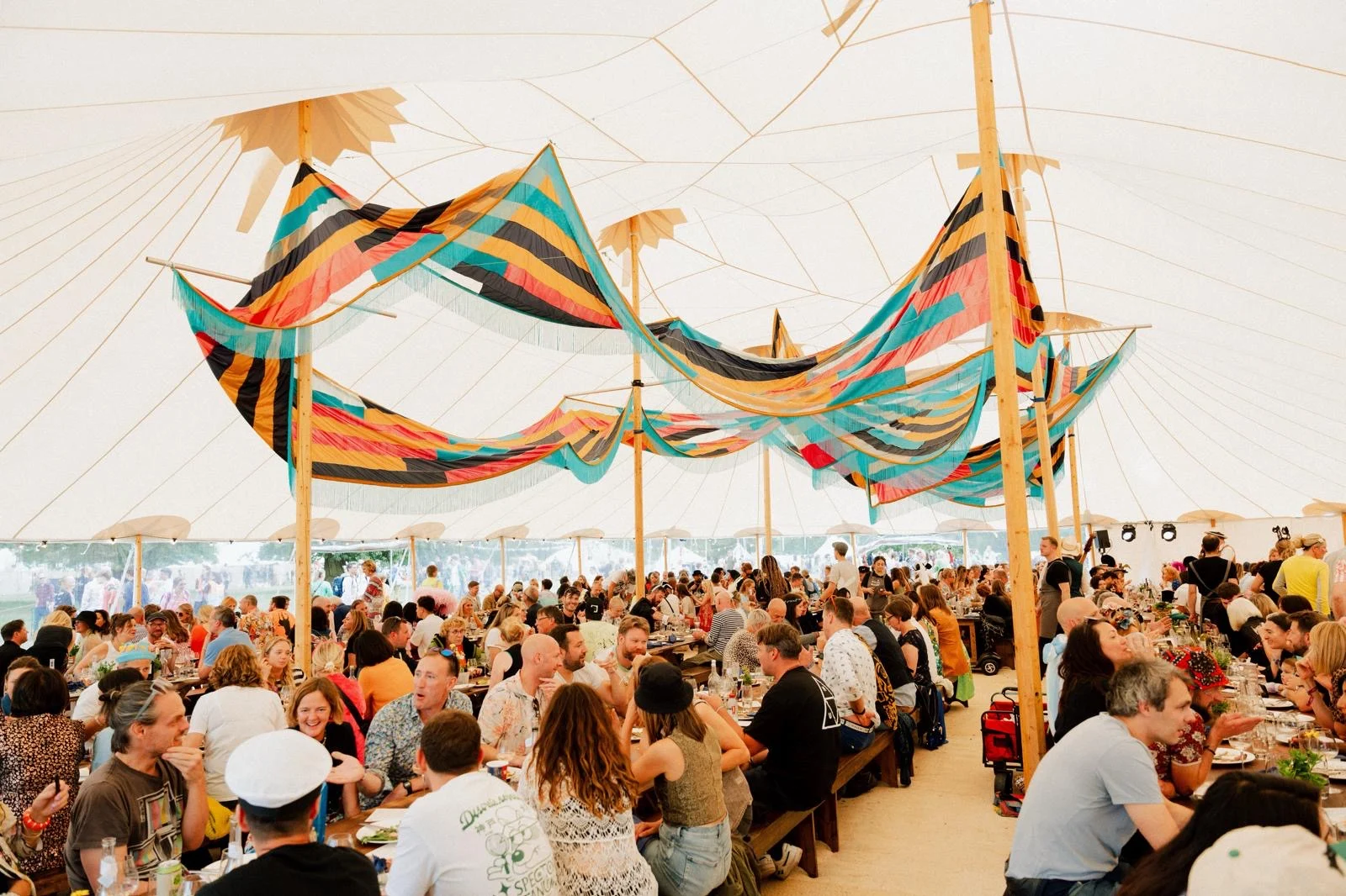 Guests dining under colourful fabric decorations in a marquee — example for events in Hale