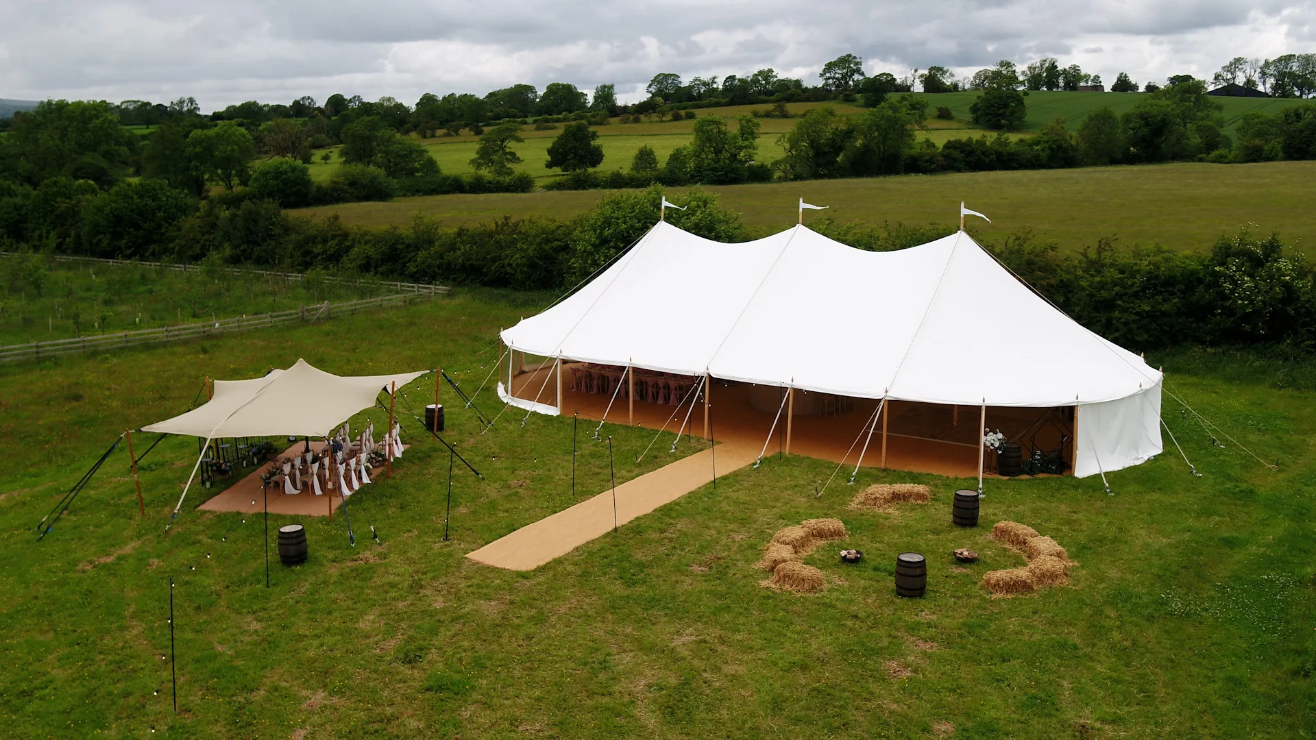 White sailcloth marquee and outdoor seating in a countryside setting