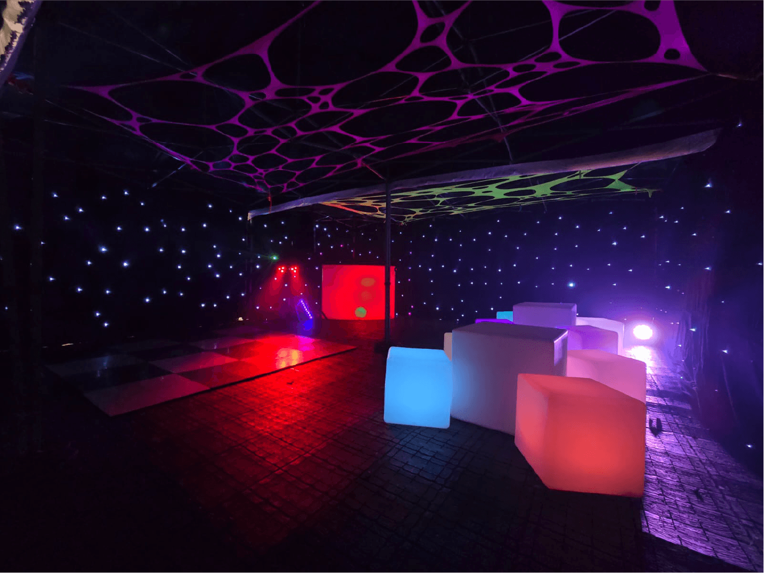 Party tent interior with red lighting and illuminated cube seats — example for events in Alderley Edge